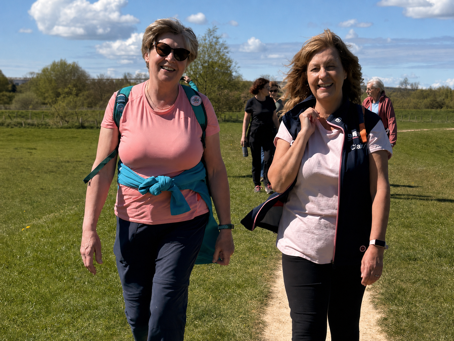 Two Adventure Geek members smiling as they walk together on a sunny countryside path.
